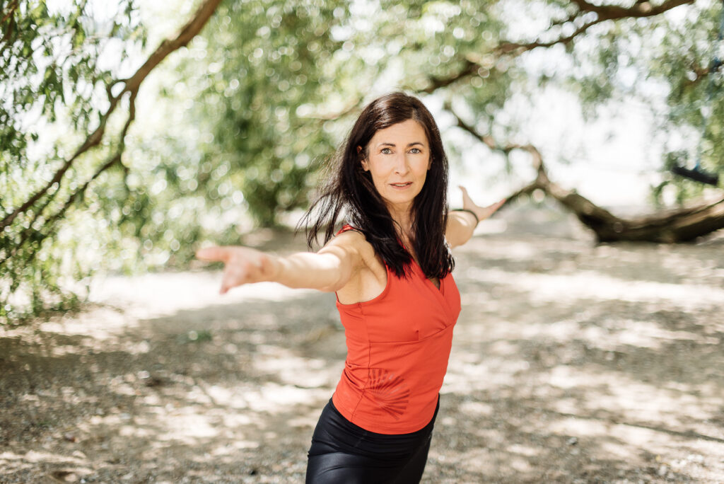 Sabine Boesinger in einer Yoga-Haltung unter Bäumen